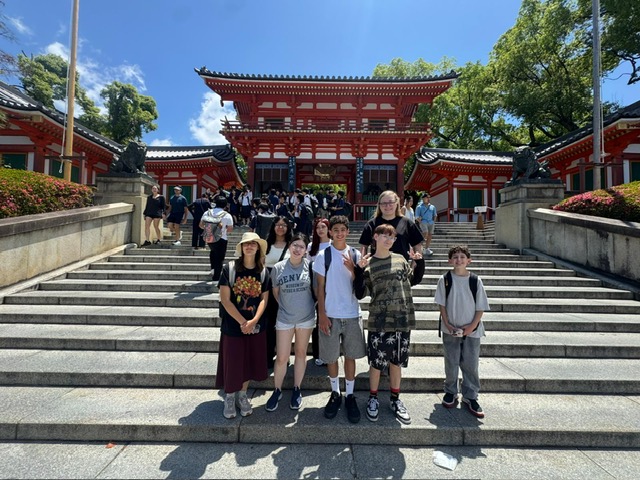 Group of tourists posing on steps at a traditional red Japanese temple